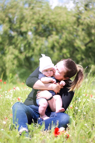 Mom in a dark blouse with a little son in her arms in the field. field of poppies. nature, spring. Summer day. — Stock Photo, Image