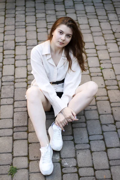 Sexy przetargu dziewczyna siedzi na chodniku płyty — Zdjęcie stockowe