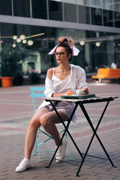 Дівчина п'є каву за столом вуличної кав'ярні — стокове фото