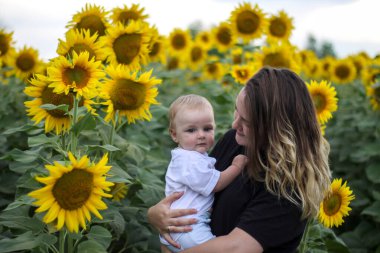 Esmer kadın, genç anne ve tatlı sarışın oğlu ayçiçeği tarlasında..