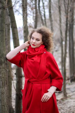 Çok üzgün, kıvırcık saçlı, yüzünde duygular olan parlak yağmurluklu bir kız..