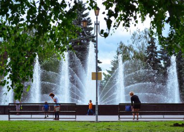 Chelyabinsk Rusya - 2 Temmuz 2015. Revolution Meydanı 'ndaki halk bahçesi. İnsanlar fıskiyenin arka planında işlerini yaparlar.