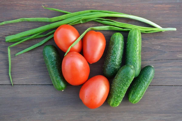 Cucumbers, tomatoes and onion on wooden table. — Stock Photo, Image