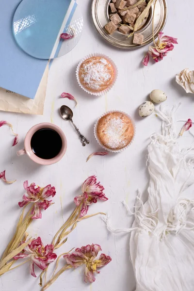 Kaffeetasse, Cupcakes mit rosa Tulpenblüten auf weißem rustikalen Tisch von oben, Frühstück am Muttertag oder Frauentag. — Stockfoto