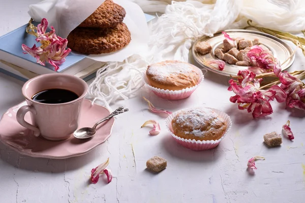 Coffee and sweet desserts, oat biscuits, cupcakes and spring flowers. Romantic breakfast.