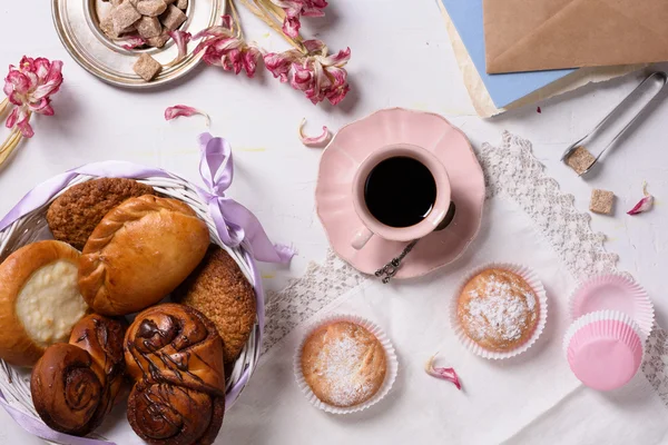 Pasticceria fresca con caffè, cupcake, fiori di tulipano rosa su sfondo bianco rustico. Vista dall'alto . — Foto Stock