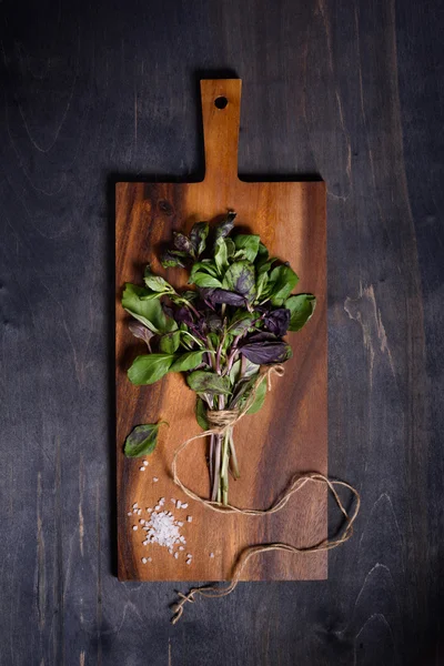 Basil, green and purple herbs, on brown wooden board, directly above. Fresh garden greens.