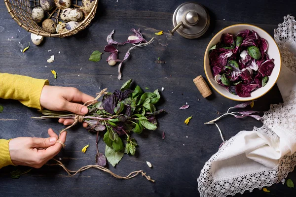 Mujer manos ensalada de cocina, albahaca fresca, hojas de radicchio y huevos. Mesa de madera, directamente encima . — Foto de Stock