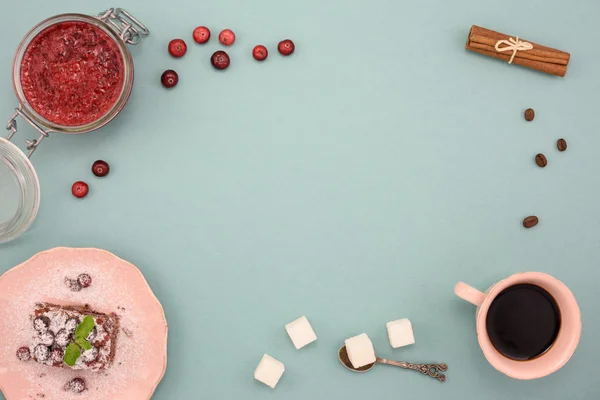 Torta di caffè e cioccolato con marmellata di mirtilli rossi e cannella su tavola di legno, su sfondo turchese. Vista dall'alto, copia spazio . — Foto Stock