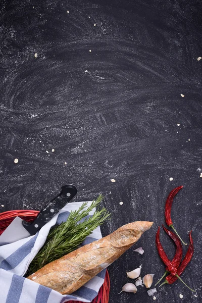 Pane appena sfornato in cesto rosso con rosmarino, aglio e peperoncino su fondo scuro. Vista dall'alto, spazio di testo libero . — Foto Stock