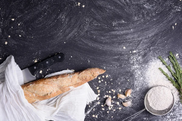 Baguette alla francese o pane rustico con rosmarino, aglio e farina su fondo lavagna di gesso. Vista dall'alto, spazio per il testo . — Foto Stock