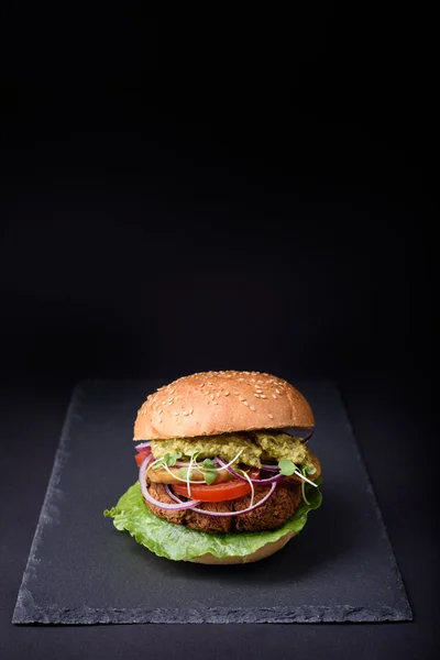 Fresh burger on black slate and turkey cutlet, sliced onion, tomato and avocado sauce served on black slate board, copy space.