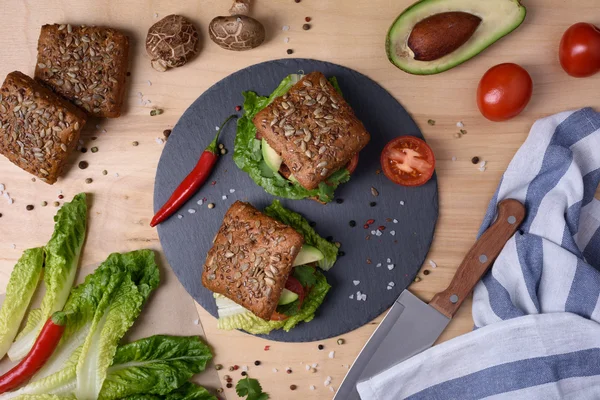 Veggie burger with shiitake, falafel and avocado, on wooden background, top view.