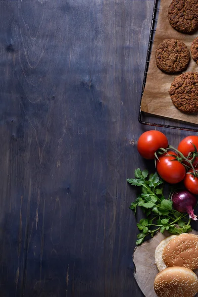 Grilled ground beef meat Burger steak cutlets with seasoning, tomatoes, parsley and bun on wooden table, space for text.