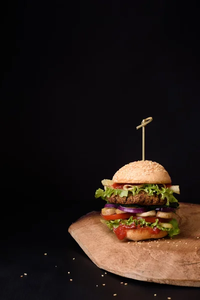 Lezzetli burger rustik ahşap tahta, koyu arka plan üzerinde. Kopya alanı.