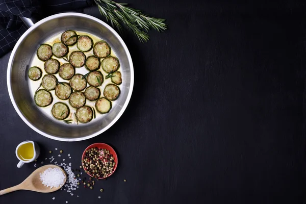 Vegetarian dish, zucchini and rosemary, over dark wooden background. Flat lay, copy space. — Stock Photo, Image