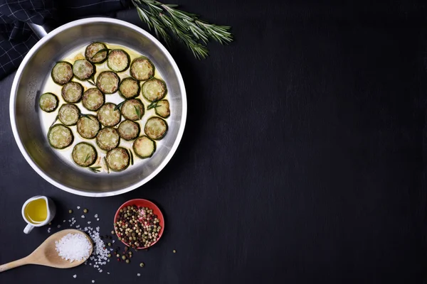 Plat végétarien, courgettes et romarin, sur fond bois foncé. Pose plate, espace de copie . — Photo