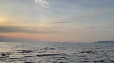 Adriyatik Denizi üzerindeki ılık günbatımı renkleri yumuşak sakin dalgalar ve geniş deniz ufkuyla. Huzurlu bir akşam manzarası doğa görsellerini rahatlatmaya uygun..