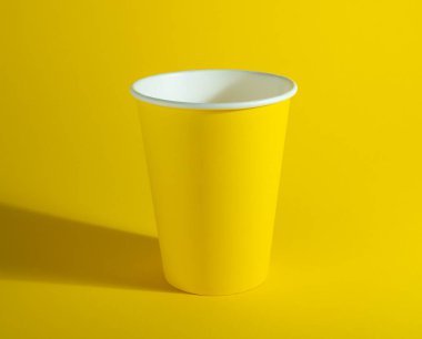 Sarı kağıt bardak, sarı arka planda tek kullanımlık bardak..