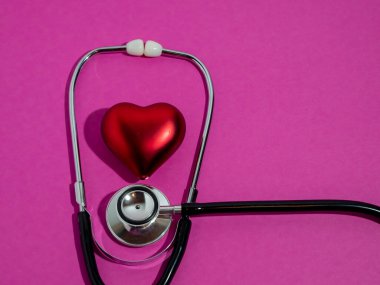 Pembe arka planda kırmızı kalp ve steteskop..