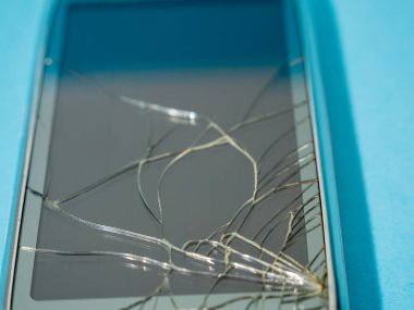 Bozuk ekranlı siyah akıllı telefon ve serviste mavi bir masanın üzerinde ceset..