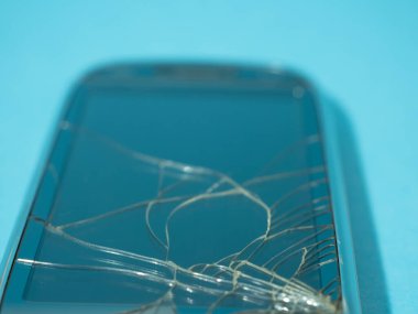 Bozuk ekranlı siyah akıllı telefon ve serviste mavi bir masanın üzerinde ceset..