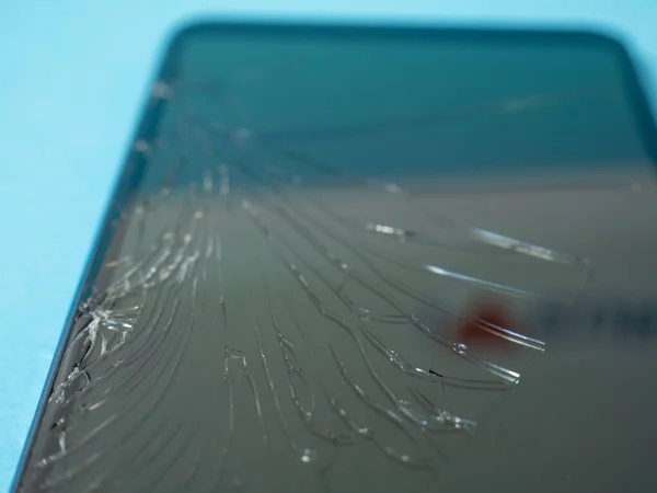 Μαύρο συνετρίβη smartphone με σπασμένη οθόνη και το σώμα σε ένα μπλε τραπέζι στην υπηρεσία. — Φωτογραφία Αρχείου