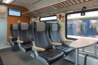 Masalı deri koltuklar. Siyah deri tren koltukları modern bir masa etrafında düzenlenir. Pencere, aşağıdaki soketlerle dışarıda bir görünüm sağlar.