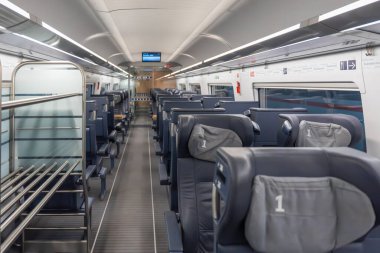 Birinci sınıf tren. Geniş görüş. Deri koltukları ve üst rafları olan birinci sınıf geniş bir vagon. Koridor görünümü konforu ve modern tasarımı vurgular.