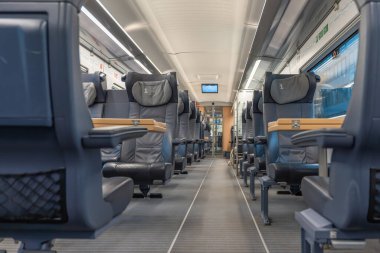 Geniş deri koltukları ve katlanabilir masaları olan modern birinci sınıf tren vagonu. İçerisi temiz, parlak ve uzun yolculuklarda rahat etmek için tasarlanmış..