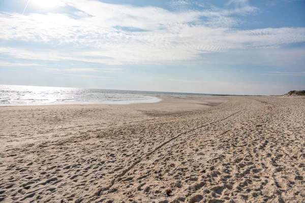 A bright sandy beach meets the glittering sea under a radiant sky. Gentle waves and sunlight create a feeling of freedom and peace.