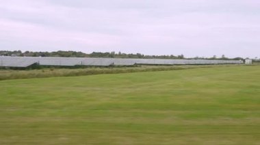 Güneş Tarlaları ve Açık Çayırlık. Yumuşak mor bulutların altından güneş panelleri olan geniş bir alan geçiyor. Düz kuzey manzarası mesafeye kadar uzanıyor..