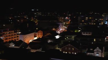 Aydınlanmış caddeler ve binalar üzerinde sessiz bir gece manzarası. Modern ve klasik yüzlerin karışımı şehrin ışıkları altında parlıyor..