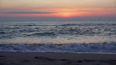 Dalgalar gün batımında zarif bir şekilde hareket eder. Yavaş çekim okyanusları yakalar. Derin renkler, sıcak akşam ışığı ile harmanlanır..