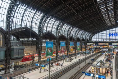 Almanya Hamburg 26 Ekim 2025. Kemerli çelik çatılı tren istasyonu. Geniş bir tren istasyonu. Birden fazla rayların üzerinde cam ve çelik kasalar var. Gezginler ve gezginler dinamik bir şehir manzarası yarattılar.