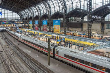 Almanya Hamburg 26 Ekim 2025. Birden fazla treni olan istasyon platformları. Göçmen bürosu ve büyük cam çatı altında bölgesel trenlerle dolu demiryolu platformları. Gezginler canlı bir atmosferde platformlar arasında hareket ederler..