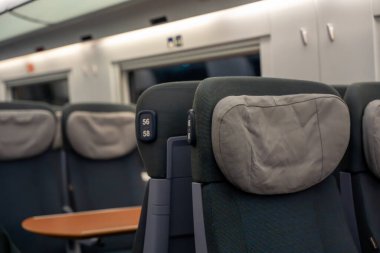 Tren koltuğu iç kısmı. Modern bir vagonda numaralandırılmış başlıkları olan rahat tren koltukları. Yumuşak ışıklandırma ve nötr tonlar sakin bir yolculuk atmosferi yaratır.