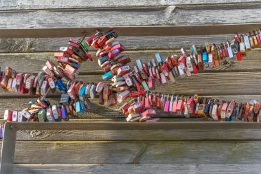 Aşk tahtaya kilitlenir. Ahşap bir yapıya bağlanmış renkli aşk kilitleri kalp şekli oluşturur. Deniz kenarındaki aşk ve hatıraların sembolleri..