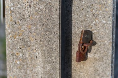 Duvardaki paslı asma kilit. Beton duvarda asılı tek bir paslı asma kilidin yakın çekimi. Zamanın, tuzun ve unutulmuş anıların işareti..