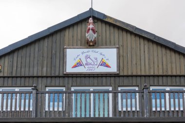 Almanya Sylt 27 Ekim 2025. Balkonlu ahşap bir bina ve üzerinde Lister Yat Kulübü Sylt yazan bir tabela. Girişin üzerine küçük bir heykel monte edildi..