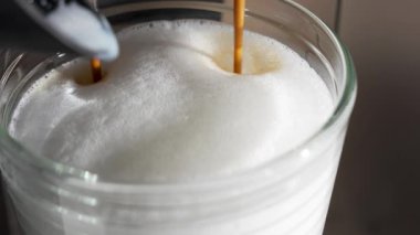 Espresso süt köpüğü yığınına akar. İpeksi bluzun altında koyu kahve kıvrılır..