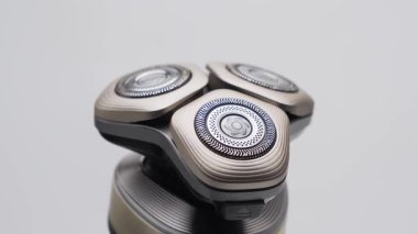 Premium elektrikli traş makinesi bir stüdyo çekiminde döner. Yan çekimde üçlü kesim elementleri ve desenli koruma halkaları üzerinde yoğunlaşıldı.