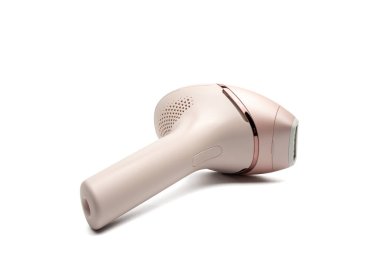 Beyaz arka planda yan yatmış IPL tüy dökücü cep telefonu. Kapalı kafanın yakın görüntüsü ve kabzada şarj oluyor..