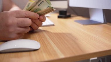 Eller, masanın üzerindeki bir bilgisayar faresinin yanında bir tomar euro banknotunu sayar. Çevrimiçi kazanç, serbest gelir veya ev ofis finansmanı kavramı.