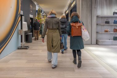 Almanya 21 Kasım 2025. Paltolu bir grup alışverişçi, KadeI koridorunda Noel vitrinlerine doğru yürüyorlar. Çantalar ve sırt çantaları yoğun kış alışveriş havasının altını çiziyor.