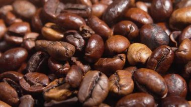 Dönen kahve çekirdeklerinin makro çekimi detaylı çatlakları ve dokuları ortaya çıkarıyor. Sıcak ışık kavrulmuş yüzeylerini vurguluyor..