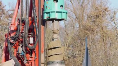 Almanya 27 Kasım 2025. Bir inşaat sahasında sondaj kulesi başı ve hidrolik hortumların yakın çekimi. Döner sürücü, arkasında ağaçlar olan çelik yığını boyunca hareket eder..