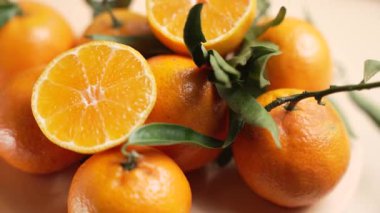 Bir mandalina yığını yarım yamalak bir kesikle dönüyor. Sahne sulu narenciye segmentleri, yapraklar ve doğal kusurları vurguluyor..