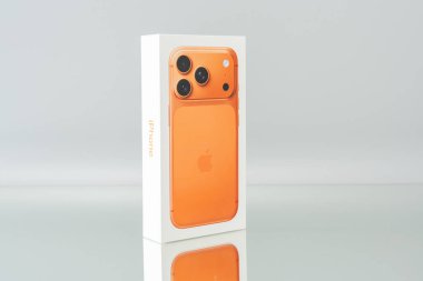 Almanya 25 Aralık 2025. Apple iPhone 17 Pro turuncu perakende paketinin açılı sunumu. Stüdyo ışıklandırması modern akıllı telefon tasarımını vurguluyor.