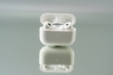 Kablosuz kulaklıklar açık bir kutunun içinde, yumuşak nötr bir arka plana karşı duruyor. Minimum ışıklandırma pürüzsüz hatları ve temiz estetiği güçlendirir.